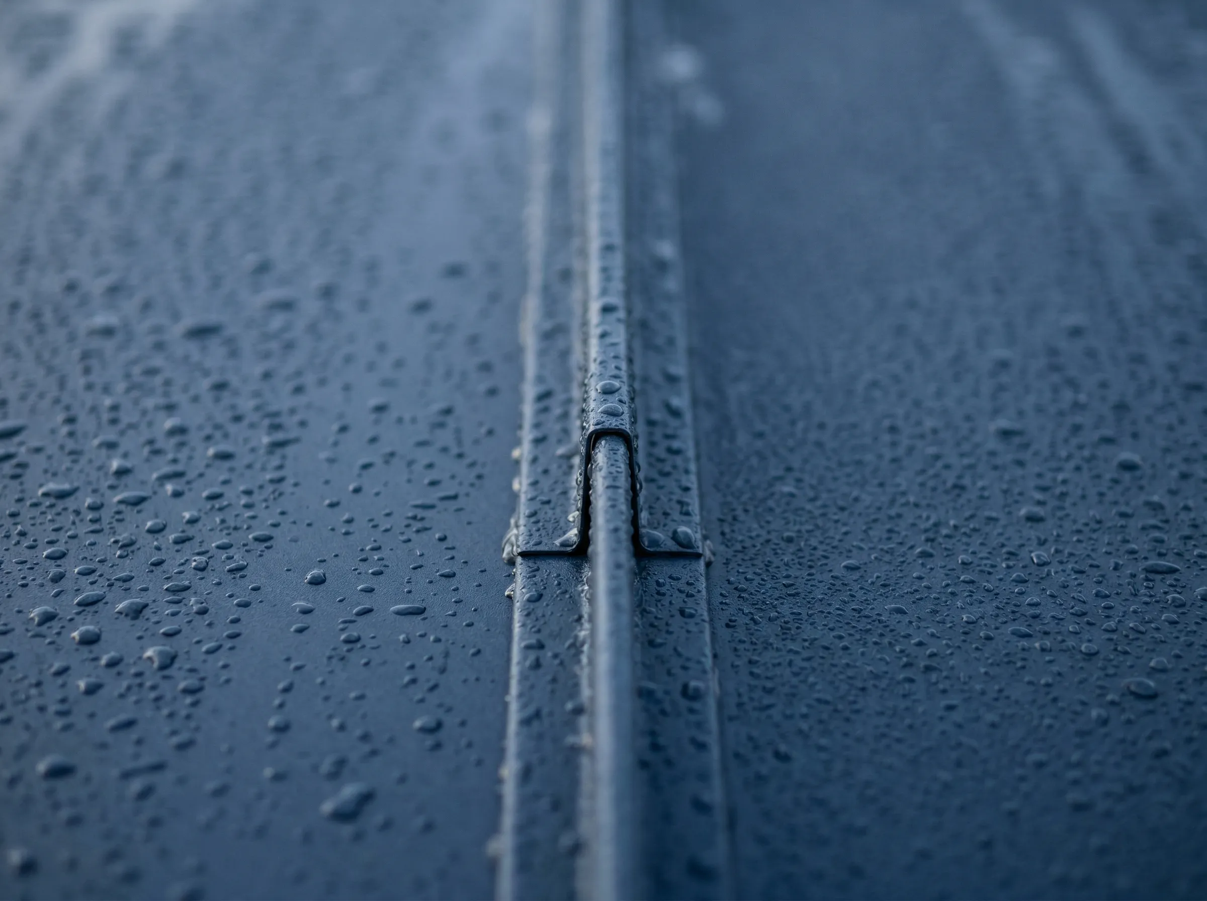 Dark aluminum standing-seam roofing with rain droplets