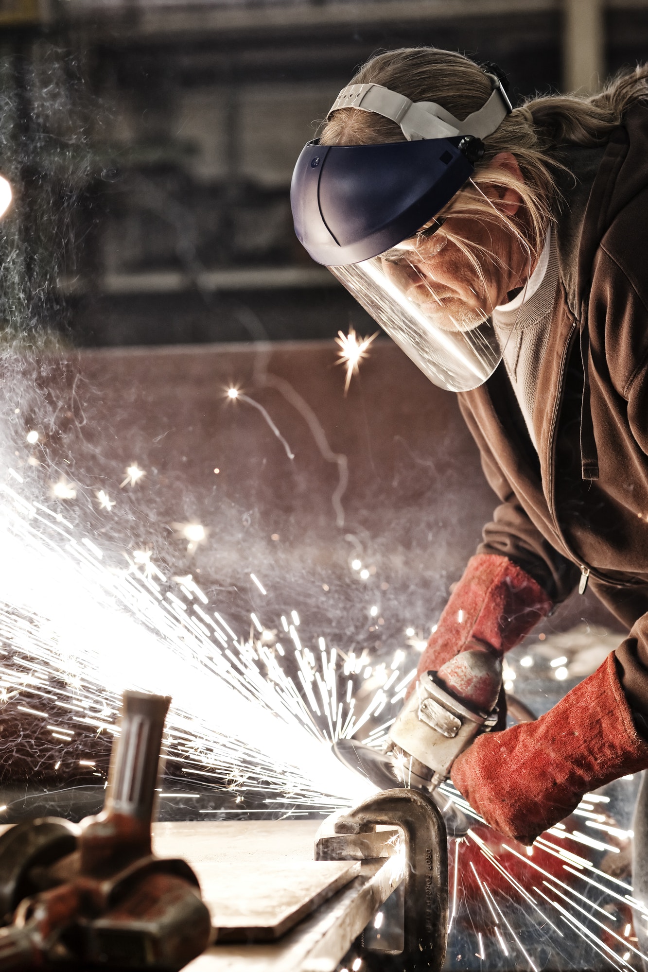 Worker finishing a steel edge in the sheet-metal factory
