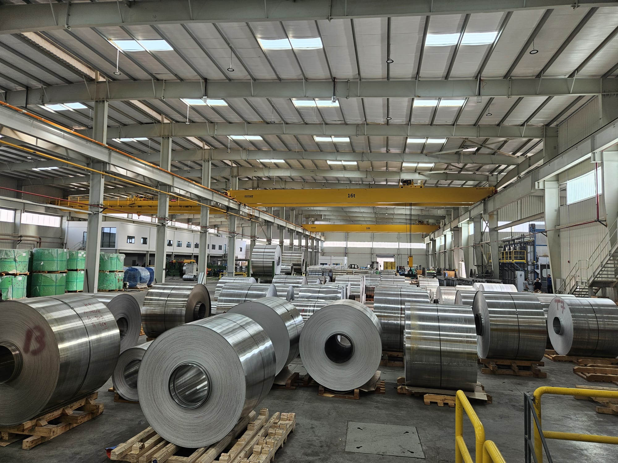 Rows of mill-finish aluminum coil stacked on skids in Orbit's Aqaba warehouse